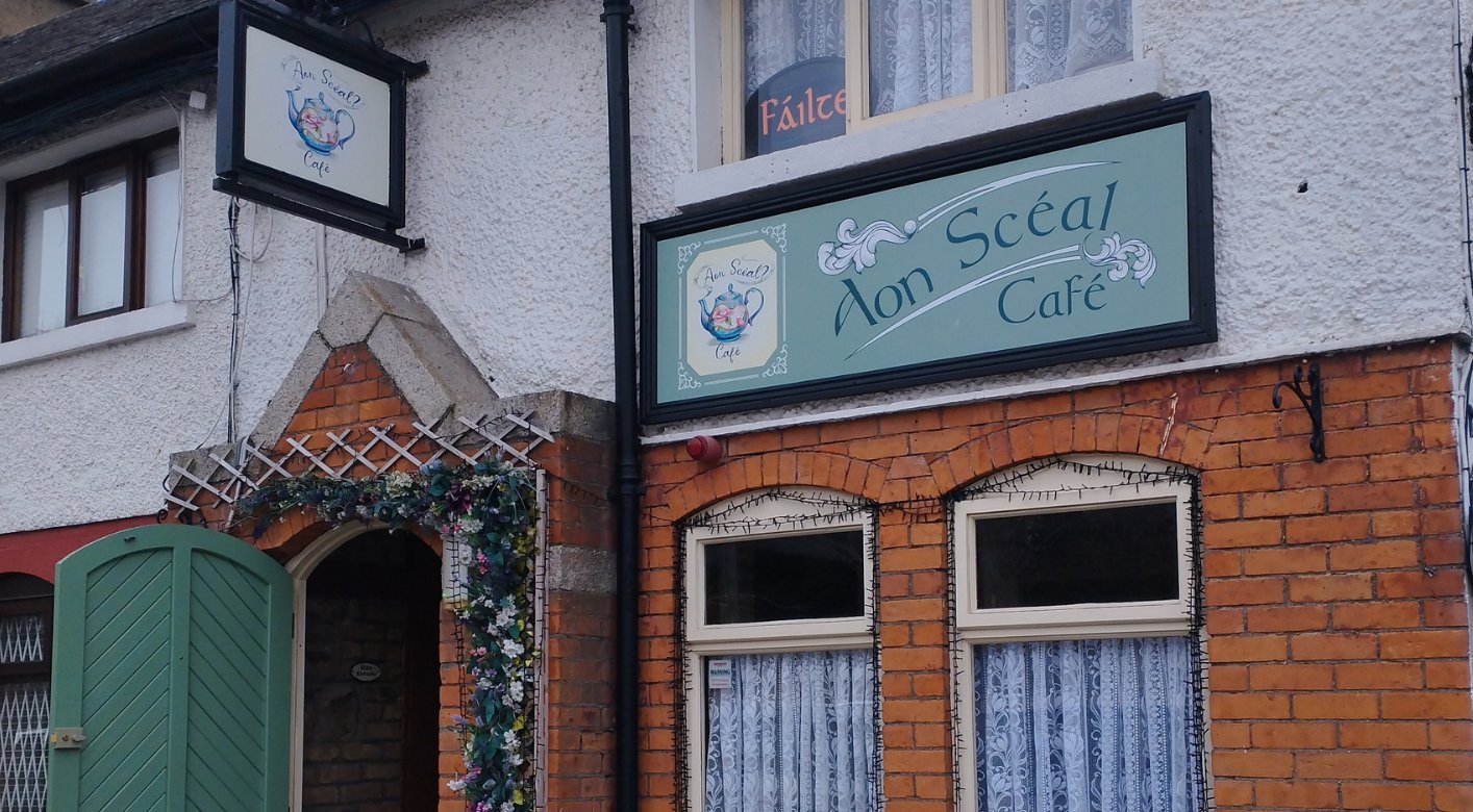 The sage-green sign, teapot logo tile and terracotta-brick front of Aon Scéal? Café on Tallaght's Main Street